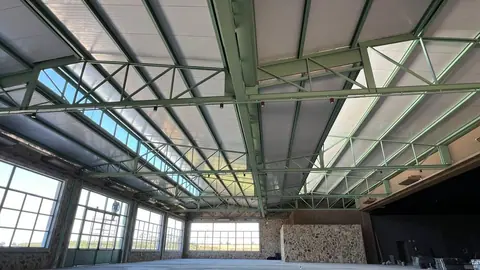 Interior de galpão com cobertura metálica e grandes vãos envidraçados