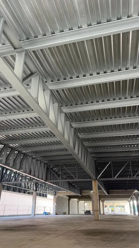 Estrutura metálica de um galpão industrial em fase de construção, com vigas de aço e piso de concreto.
