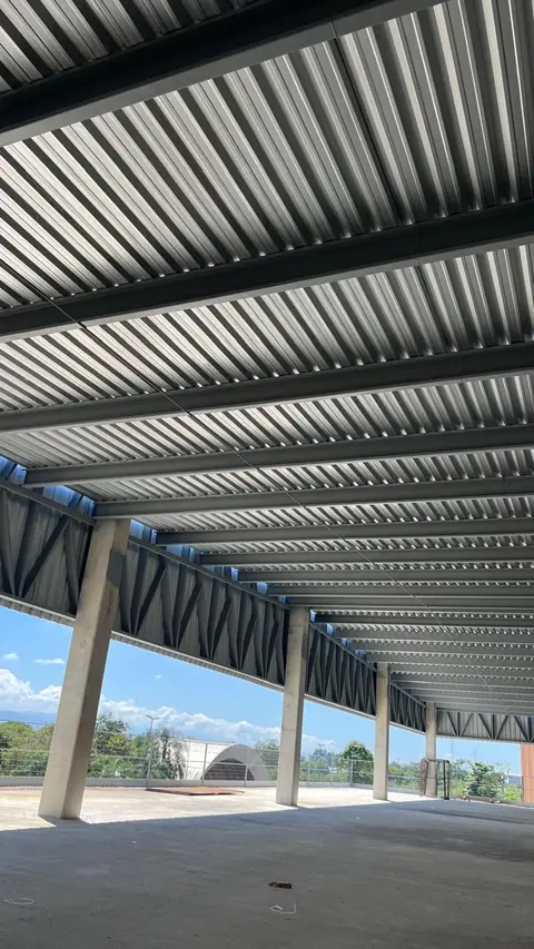 Um galpão industrial em construção com estrutura metálica aparente e piso de concreto.