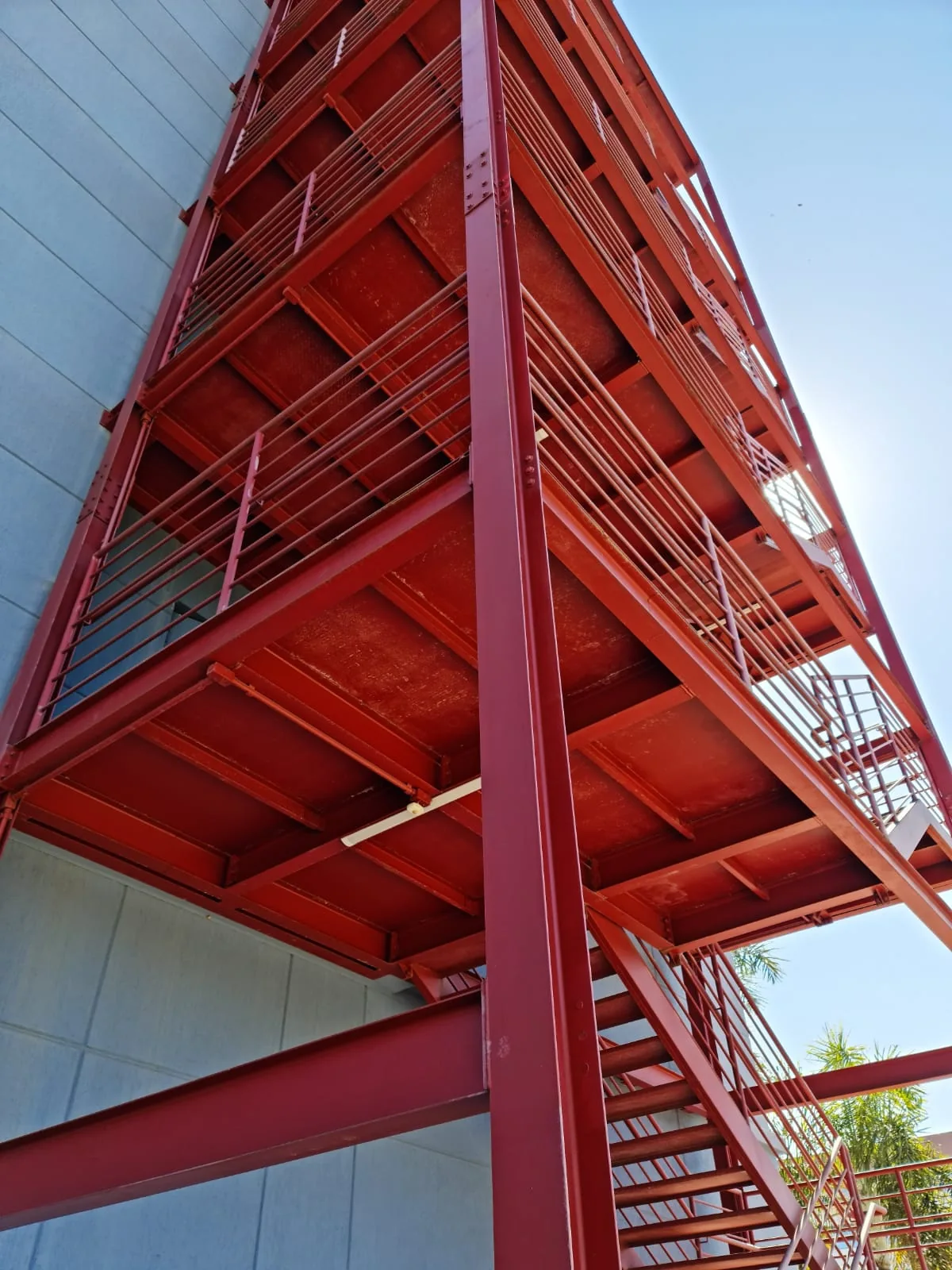 Vista inferior de escada externa metálica vermelha em edifício