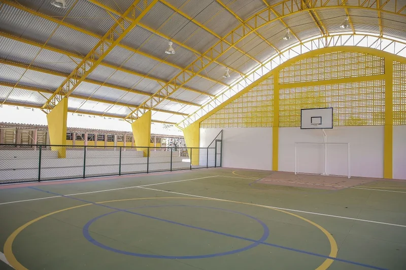 Quadra coberta com estrutura metálica amarela e linhas de jogo