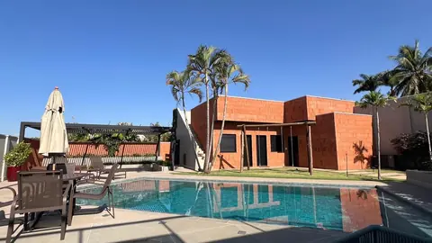 Fotografia de uma casa moderna de tijolos aparentes com piscina e área de lazer externa.